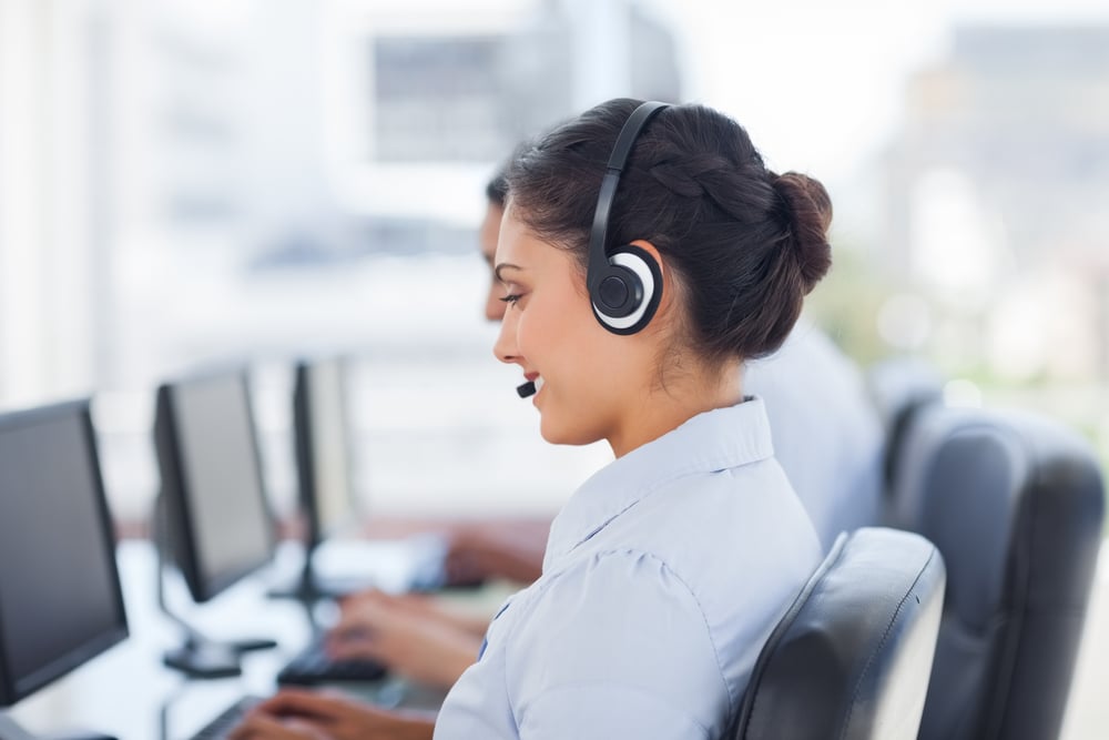 A woman in a call center smiles and responds to a message on her screen