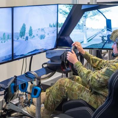 Person sitting in a military land vehicle simulator with three screens