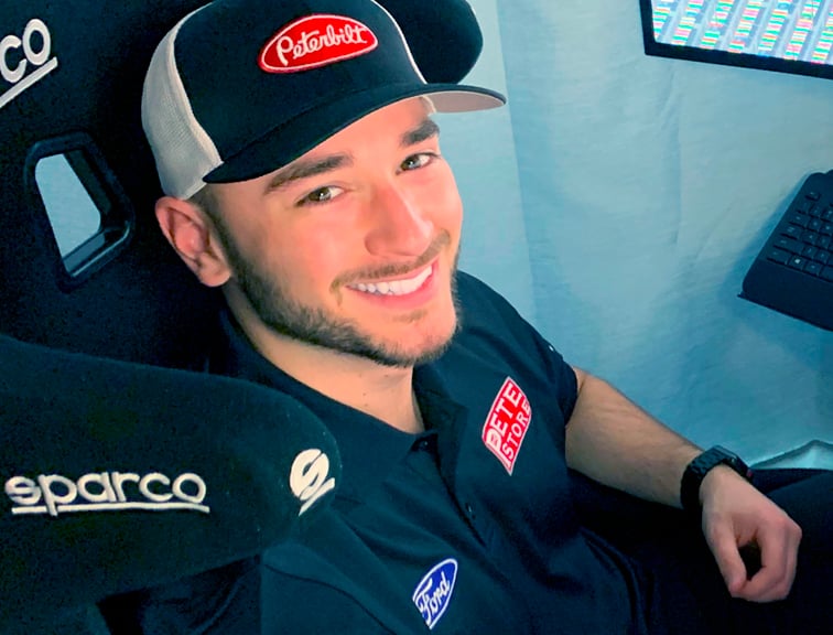 Anthony Alfredo smiles and sits in a D-BOX sim racing rig