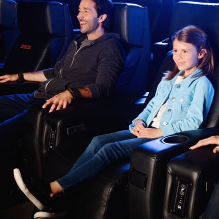 Un père et sa fille assis dans un siège inclinable de cinéma