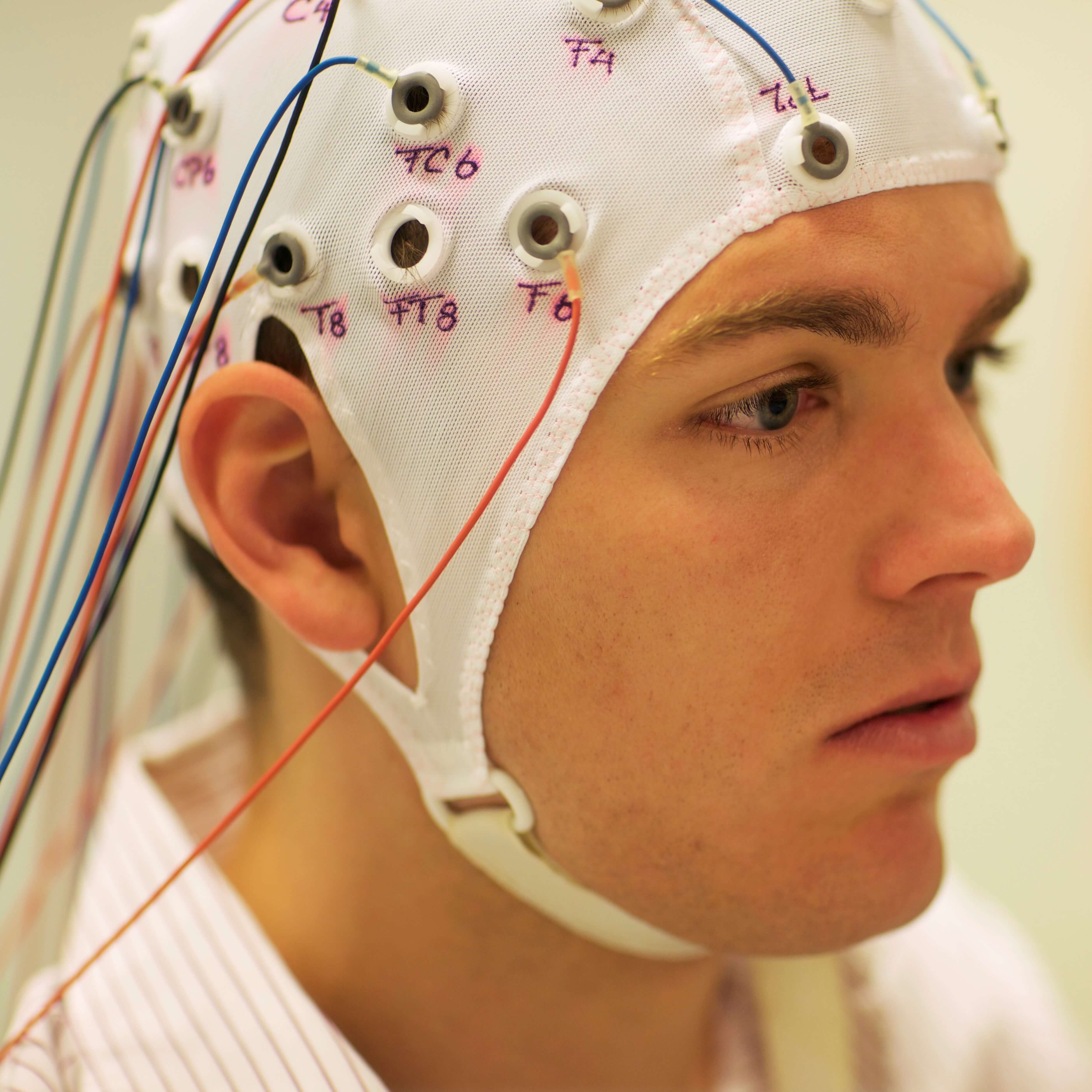 A man connected to a computer through a head cap with cables for a study